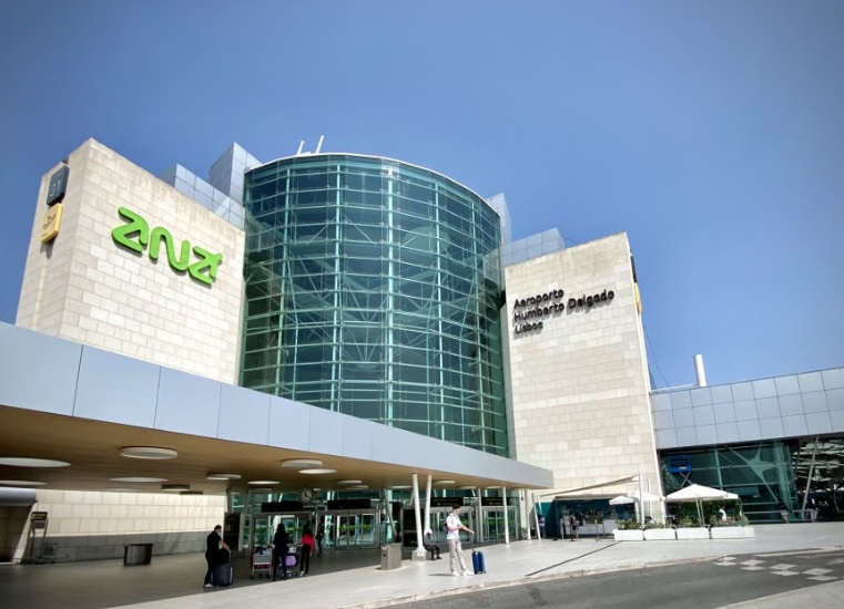 Vista do átrio de chegadas do Aeroporto de Lisboa com viajantes